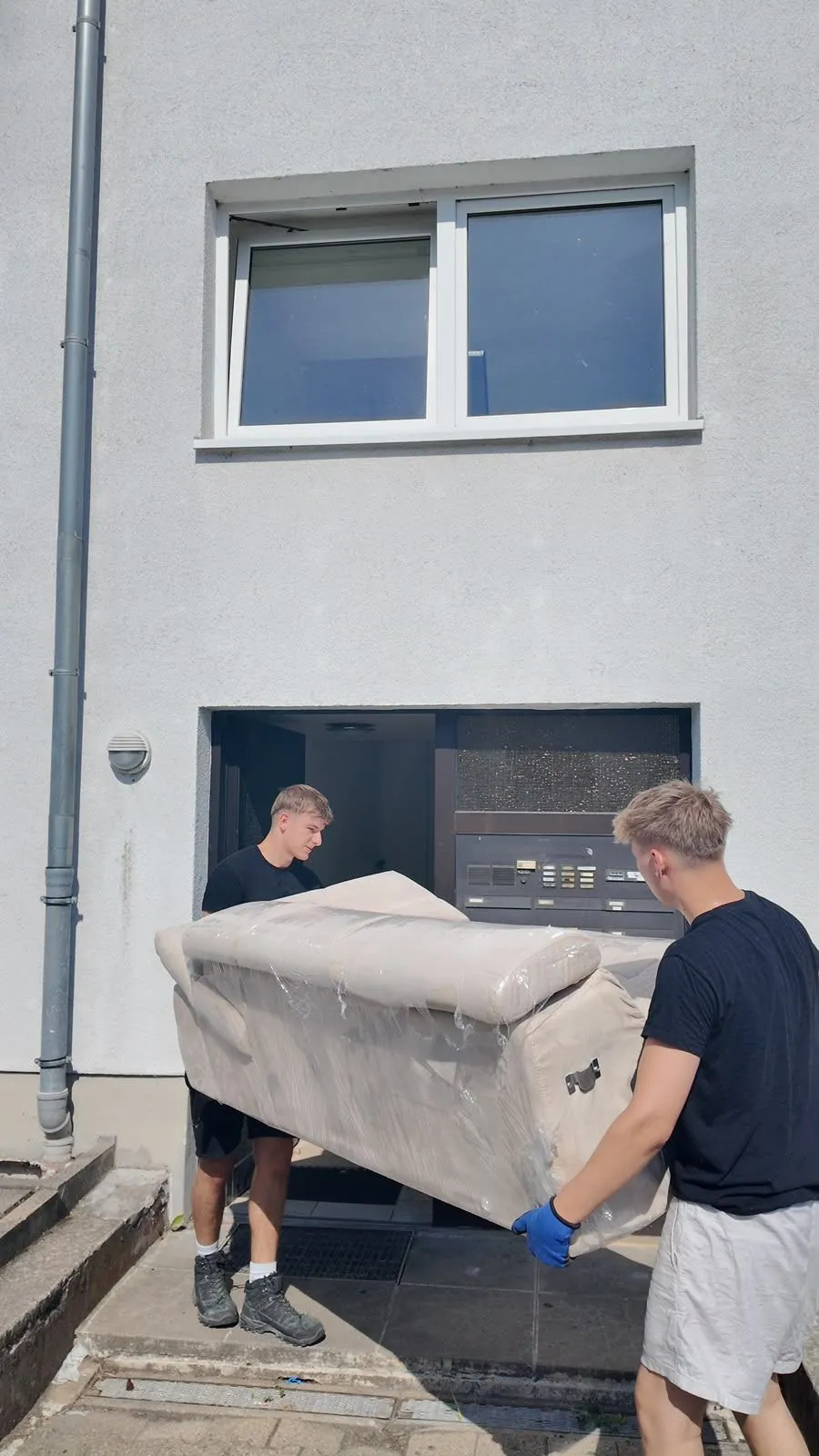 Zwei L&W-Mitarbeiter tragen ein Sofa aus einem Haus